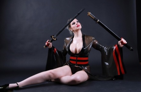 Platinum blonde solo model wields a sword while outfitted in a latex costume