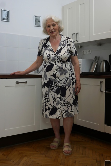 Freaky old blonde granny named Norma showing her tits in the kitchen