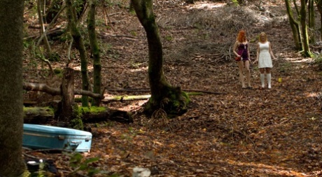 Redhead Dominatrix subjects blonde girl Dee Williams to cattle prod in woods