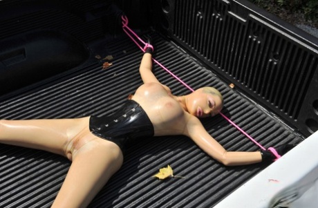 穿着乳胶的英国女孩 在 BDSM 中，乳胶露西被绑在卡车上并被喷水