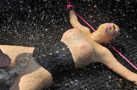穿着乳胶的英国女孩 在 BDSM 中，乳胶露西被绑在卡车上并被喷水