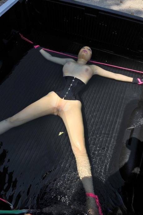 穿着乳胶的英国女孩 在 BDSM 中，乳胶露西被绑在卡车上并被喷水