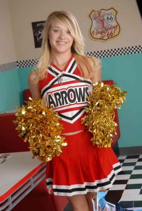 Cute college blonde Tegan Summers poses in a cheerleader outfit at a diner
