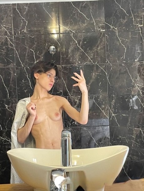 业余的黑发女孩在眼镜炫耀她的小奶子和热腹肌