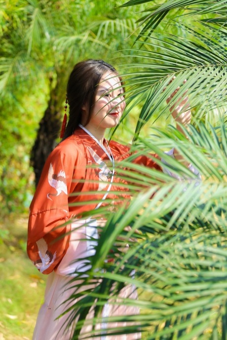 魅力四射的亚洲女孩身着中国传统服装，在大自然中搔首弄姿