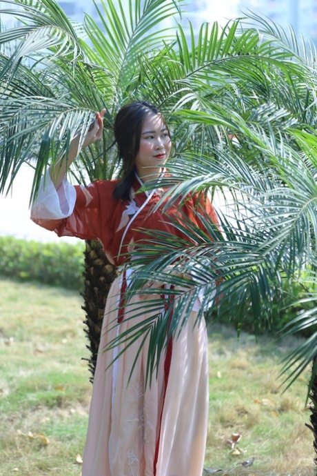 魅力四射的亚洲女孩身着中国传统服装，在大自然中搔首弄姿