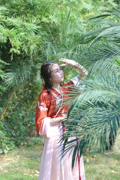 魅力四射的亚洲女孩身着中国传统服装，在大自然中搔首弄姿