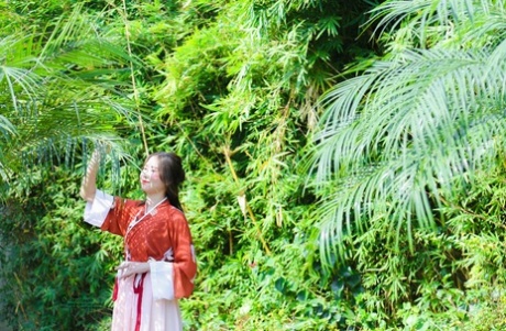 魅力四射的亚洲女孩身着中国传统服装，在大自然中搔首弄姿