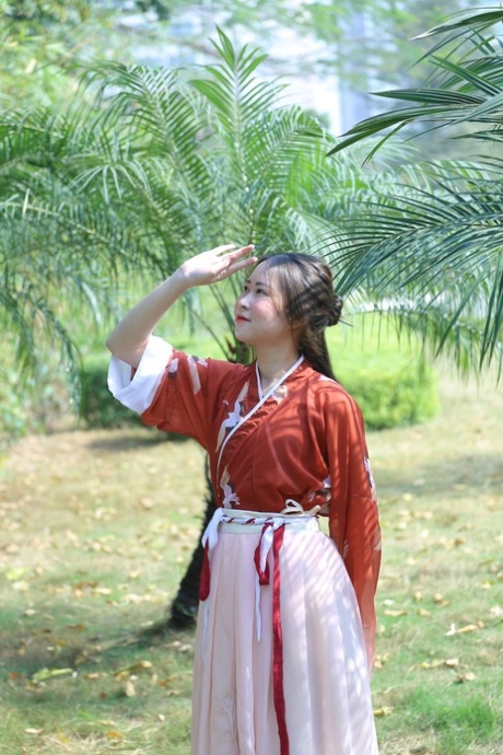 魅力四射的亚洲女孩身着中国传统服装，在大自然中搔首弄姿