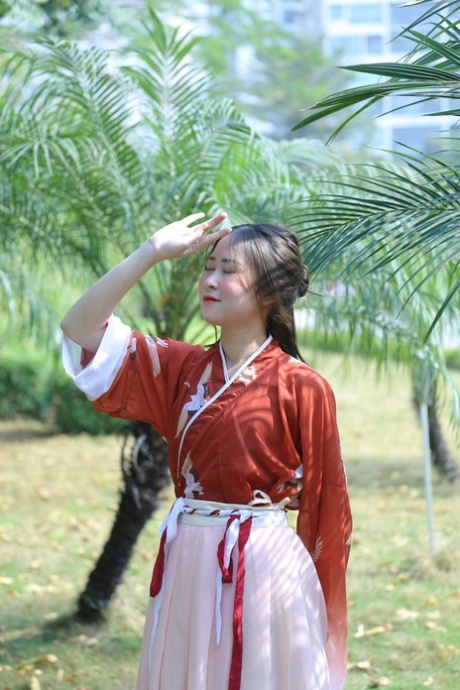 魅力四射的亚洲女孩身着中国传统服装，在大自然中搔首弄姿