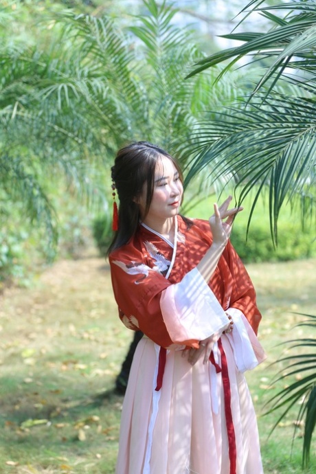 魅力四射的亚洲女孩身着中国传统服装，在大自然中搔首弄姿