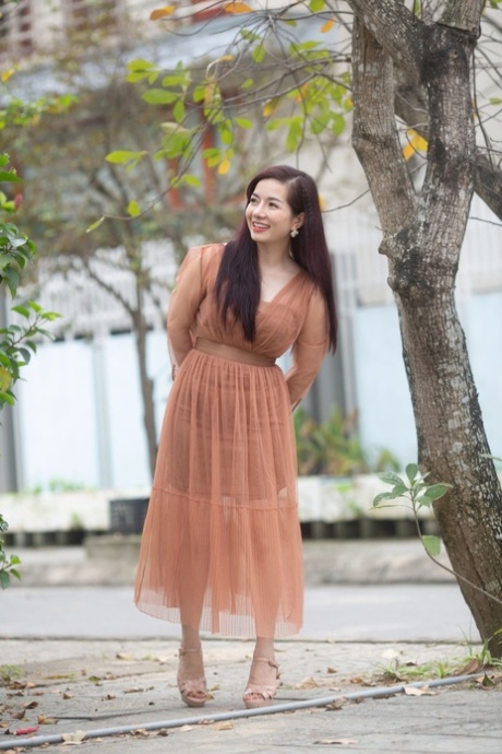 令人惊叹的亚洲模特身着性感连衣裙在公共场合独自摆姿势