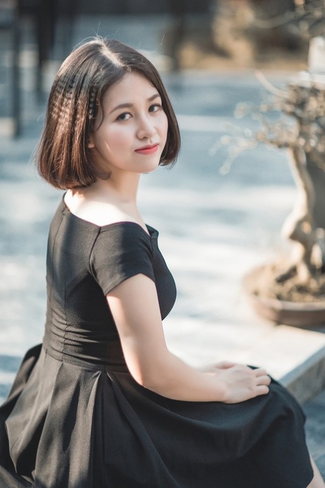 魅力四射的亚洲美女穿着优雅的黑色连衣裙在公共场合搔首弄姿