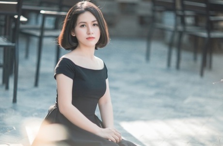 魅力四射的亚洲美女穿着优雅的黑色连衣裙在公共场合搔首弄姿