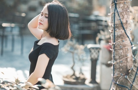 魅力四射的亚洲美女穿着优雅的黑色连衣裙在公共场合搔首弄姿