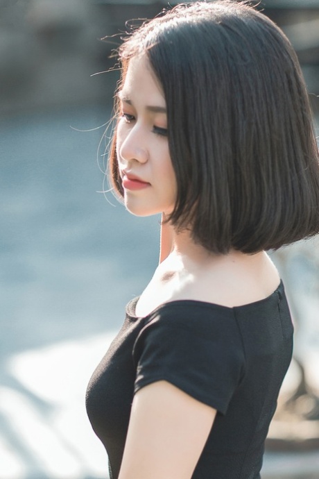 魅力四射的亚洲美女穿着优雅的黑色连衣裙在公共场合搔首弄姿