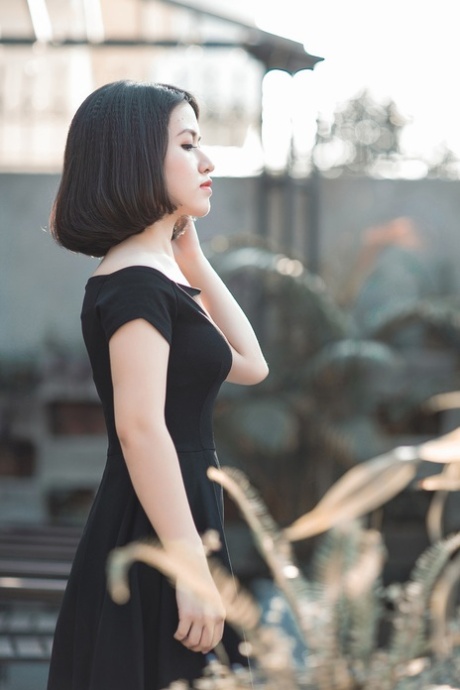 魅力四射的亚洲美女穿着优雅的黑色连衣裙在公共场合搔首弄姿