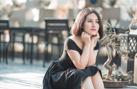 魅力四射的亚洲美女穿着优雅的黑色连衣裙在公共场合搔首弄姿