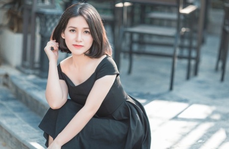 魅力四射的亚洲美女穿着优雅的黑色连衣裙在公共场合搔首弄姿