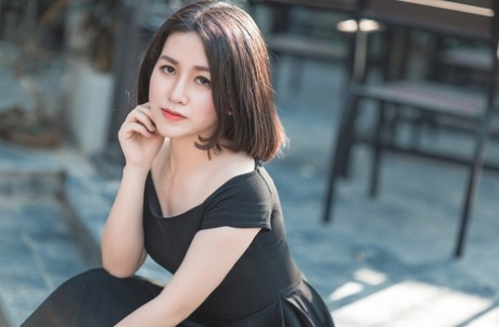 魅力四射的亚洲美女穿着优雅的黑色连衣裙在公共场合搔首弄姿