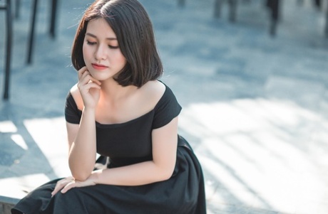 魅力四射的亚洲美女穿着优雅的黑色连衣裙在公共场合搔首弄姿