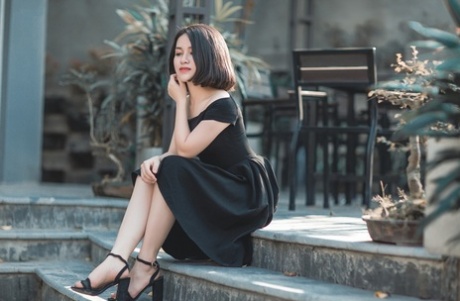 魅力四射的亚洲美女穿着优雅的黑色连衣裙在公共场合搔首弄姿
