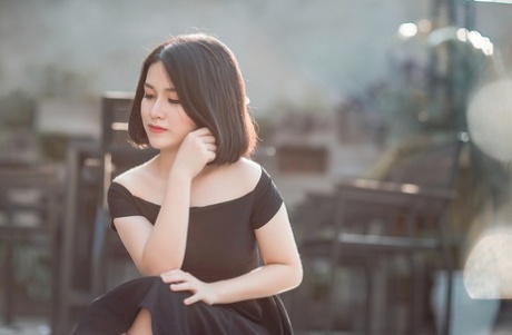 魅力四射的亚洲美女穿着优雅的黑色连衣裙在公共场合搔首弄姿