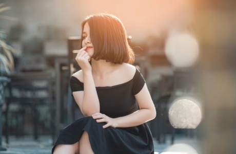 魅力四射的亚洲美女穿着优雅的黑色连衣裙在公共场合搔首弄姿