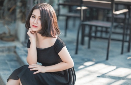 魅力四射的亚洲美女穿着优雅的黑色连衣裙在公共场合搔首弄姿