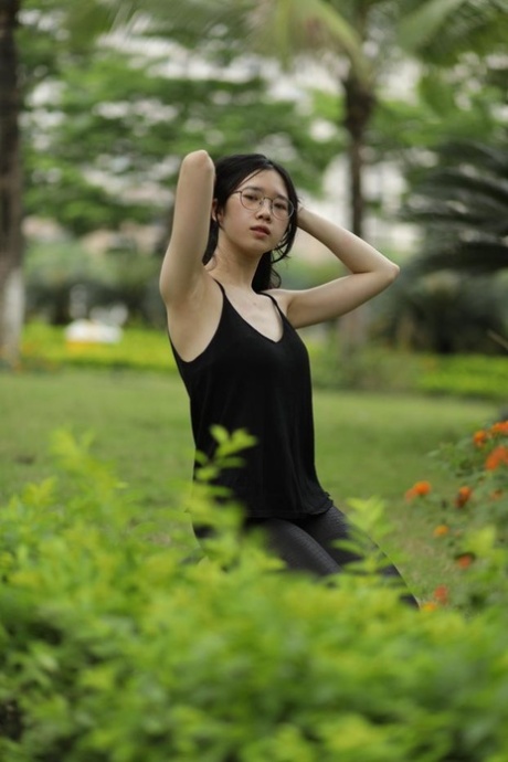 Pretty Asian girl with eyeglasses posing in her black dress at the park