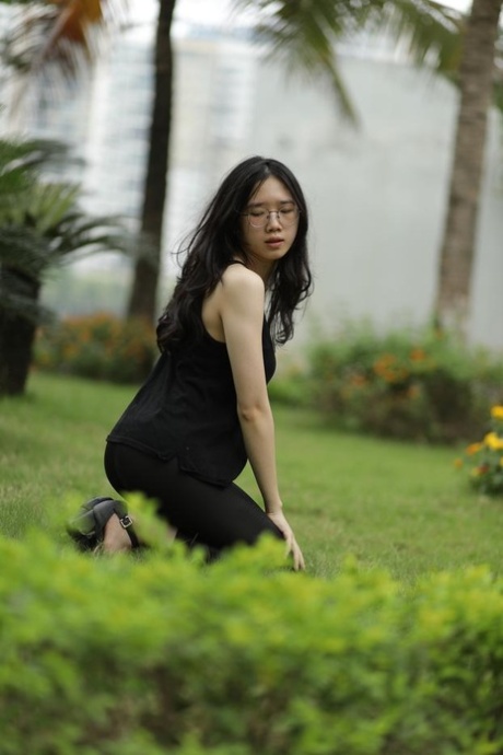 Pretty Asian girl with eyeglasses posing in her black dress at the park