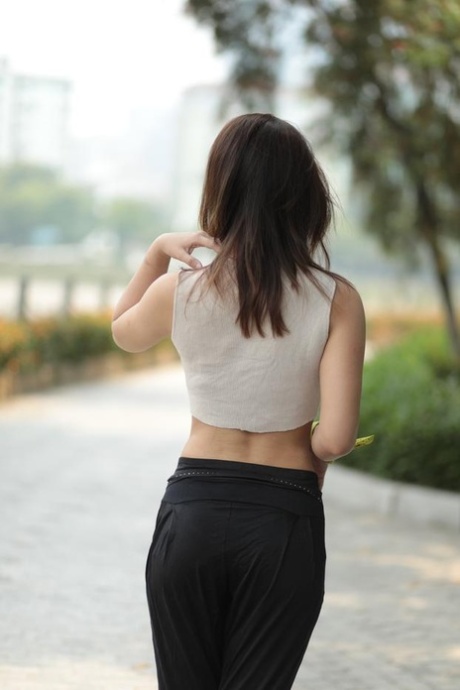 Little Asian model with eyeglasses posing in her shirt and pants outdoors