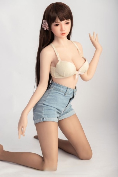 Small sex doll Leonora posing in her white bra and jean shorts in a solo