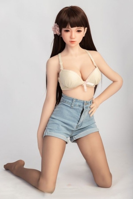 Small sex doll Leonora posing in her white bra and jean shorts in a solo
