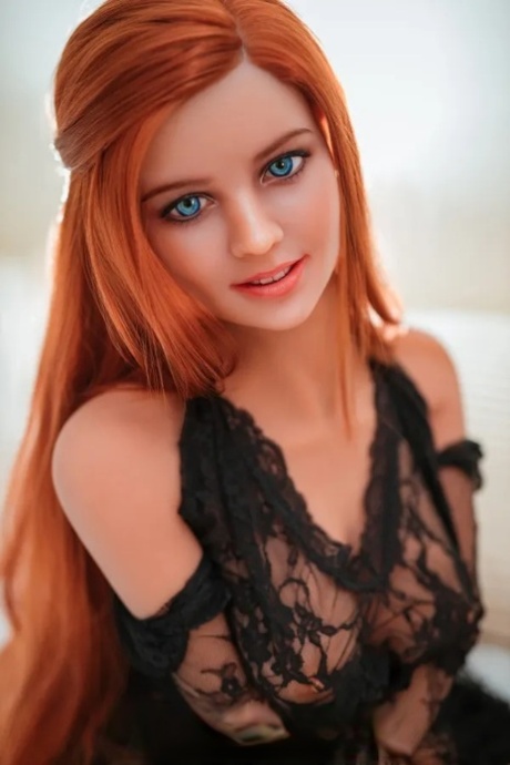 Redheaded love doll Jelena displays her big breasts and poses on a bed