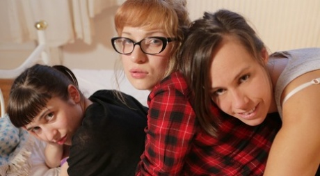 Three lesbians get dressed after engaging in strapon sex upon a bed